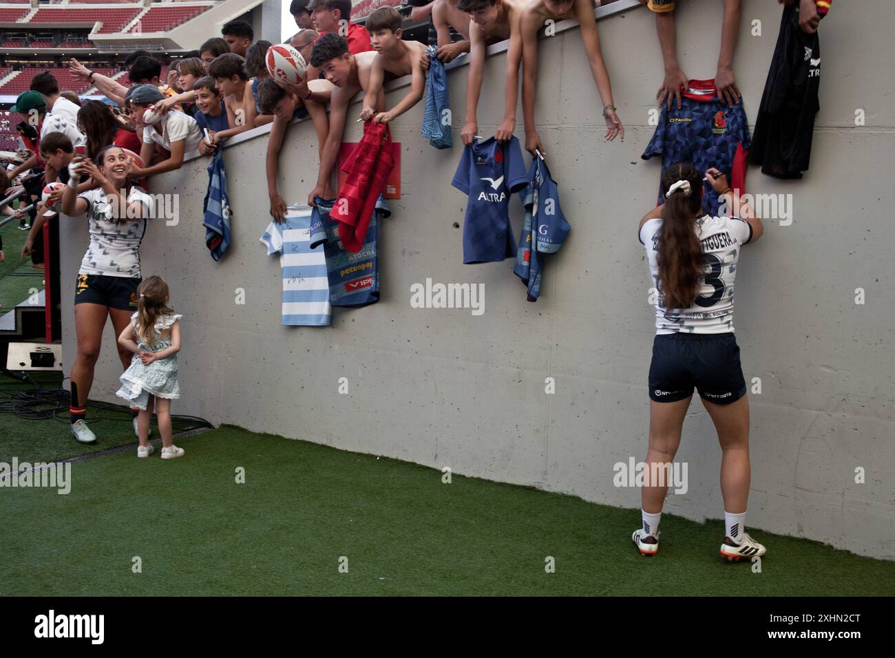 Spieler der spanischen Rugby Sevens Nationalmannschaft unterzeichnen Rugby-Trikots an Kinder nach einem Spiel während der Madrid Sevens. Stockfoto