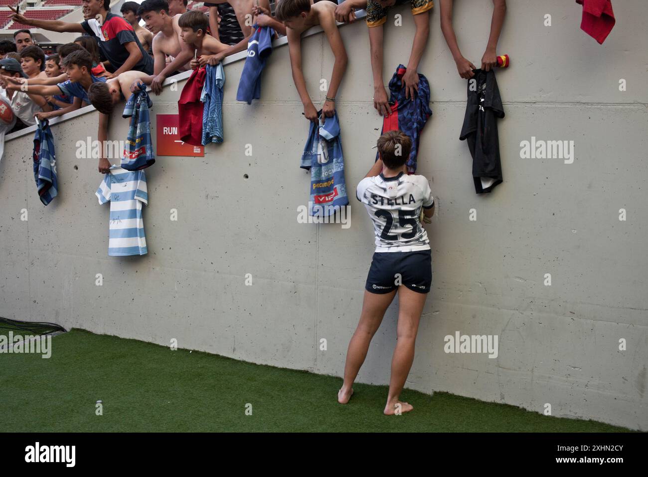 Eine Spielerin der spanischen Rugby Sevens Nationalmannschaft, die nach einem Spiel während der Madrid Sevens Rugby Trikots an Kinder signiert. Stockfoto