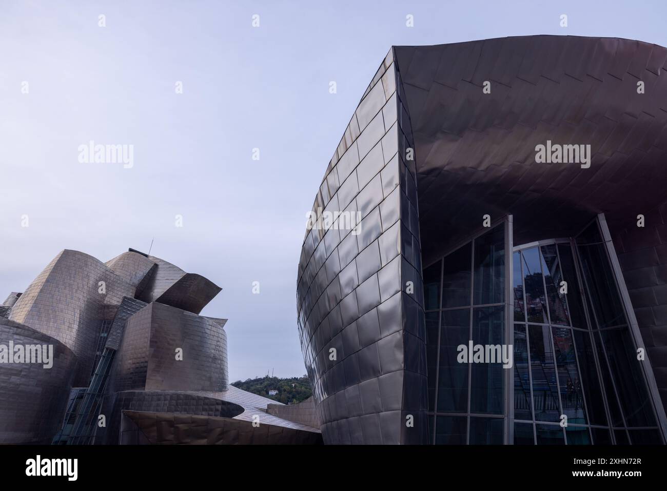 Das Guggenheim Museum in Bilbao steht stolz am Flussufer, dessen Titankurven bei Tageslicht glitzern. Stockfoto
