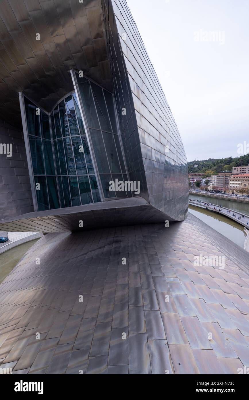 Das Guggenheim Museum in Bilbao steht stolz am Flussufer, dessen Titankurven bei Tageslicht glitzern. Stockfoto