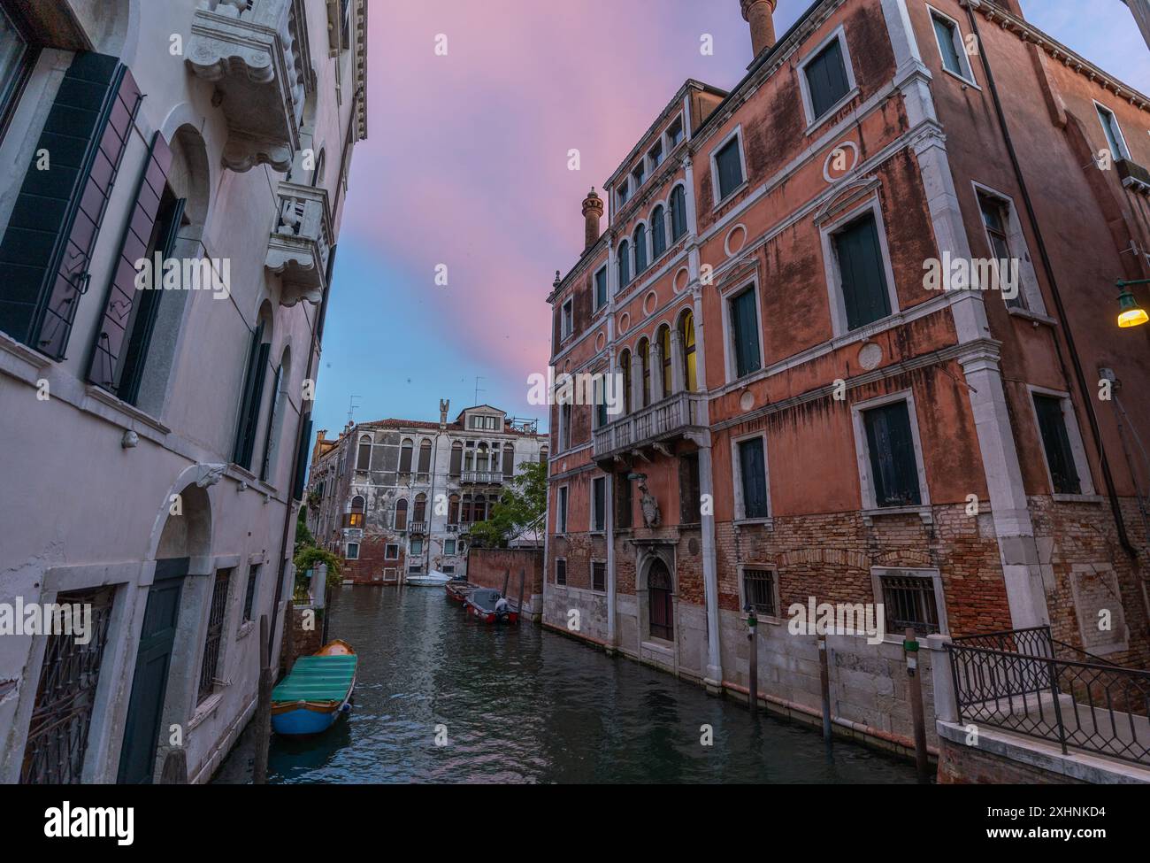 Venedig, Italien - 03. Juni 2024: Friedlicher Venedig-Kanal mit angedockten Booten, eingerahmt von bunten Gebäuden. Ruhiges Wasser mit sauberer Reflexion. Stockfoto