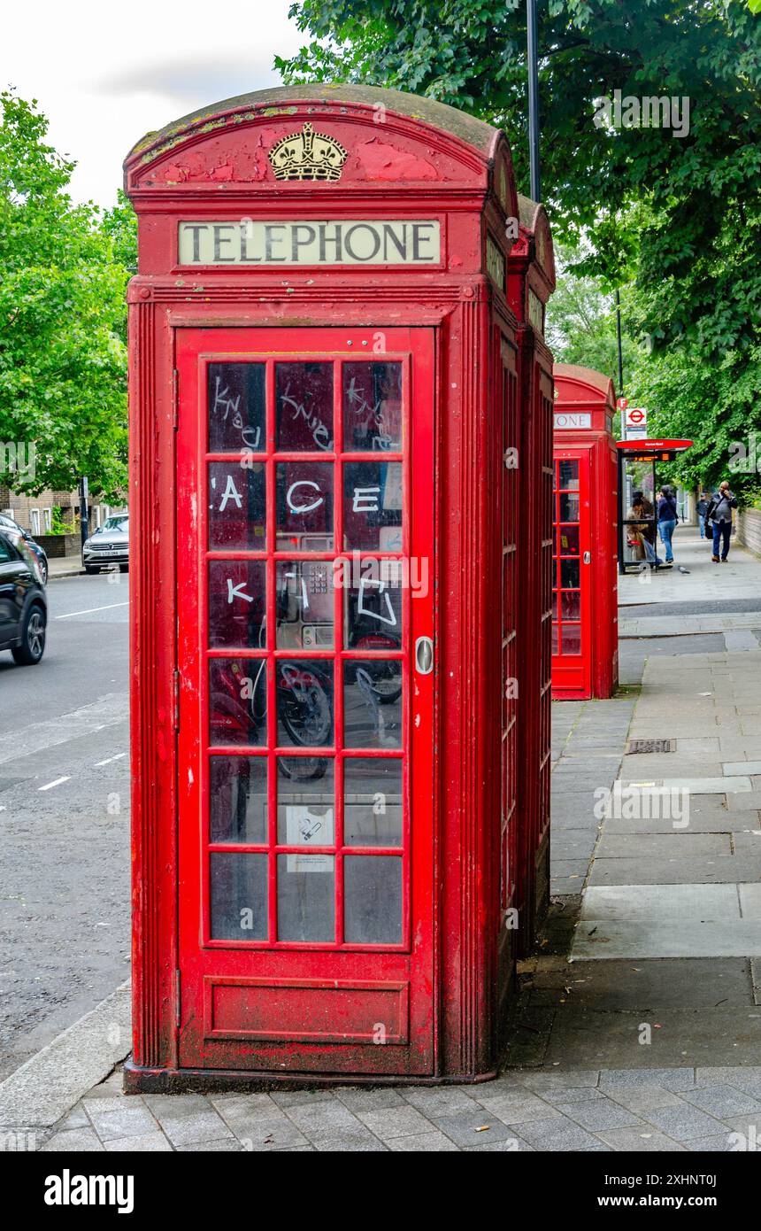 Traditionelle rote britische Telefondosen auf dem Bürgersteig an der Elgin Avenue in London, Großbritannien Stockfoto