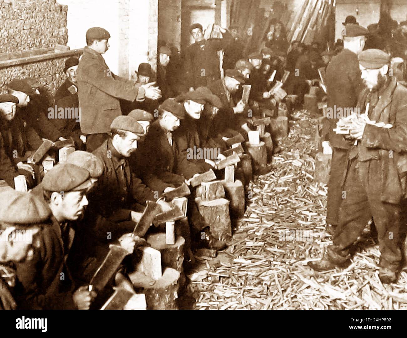 Arbeitslose Männer in London, die Sticks für Brennholz hacken, Anfang der 1900er Jahre Stockfoto