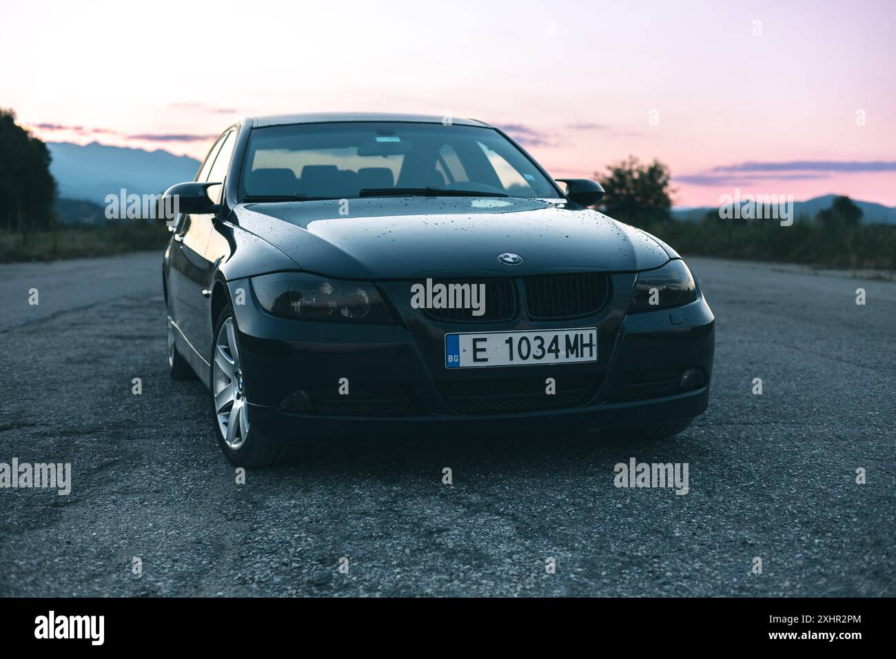 Bulgarien - 23.07.2024: Nahaufnahme der Front eines BMW E90 3er mit wunderschönem, lebendigem Hintergrundhimmel in einem verlassenen Flughafen. Stockfoto