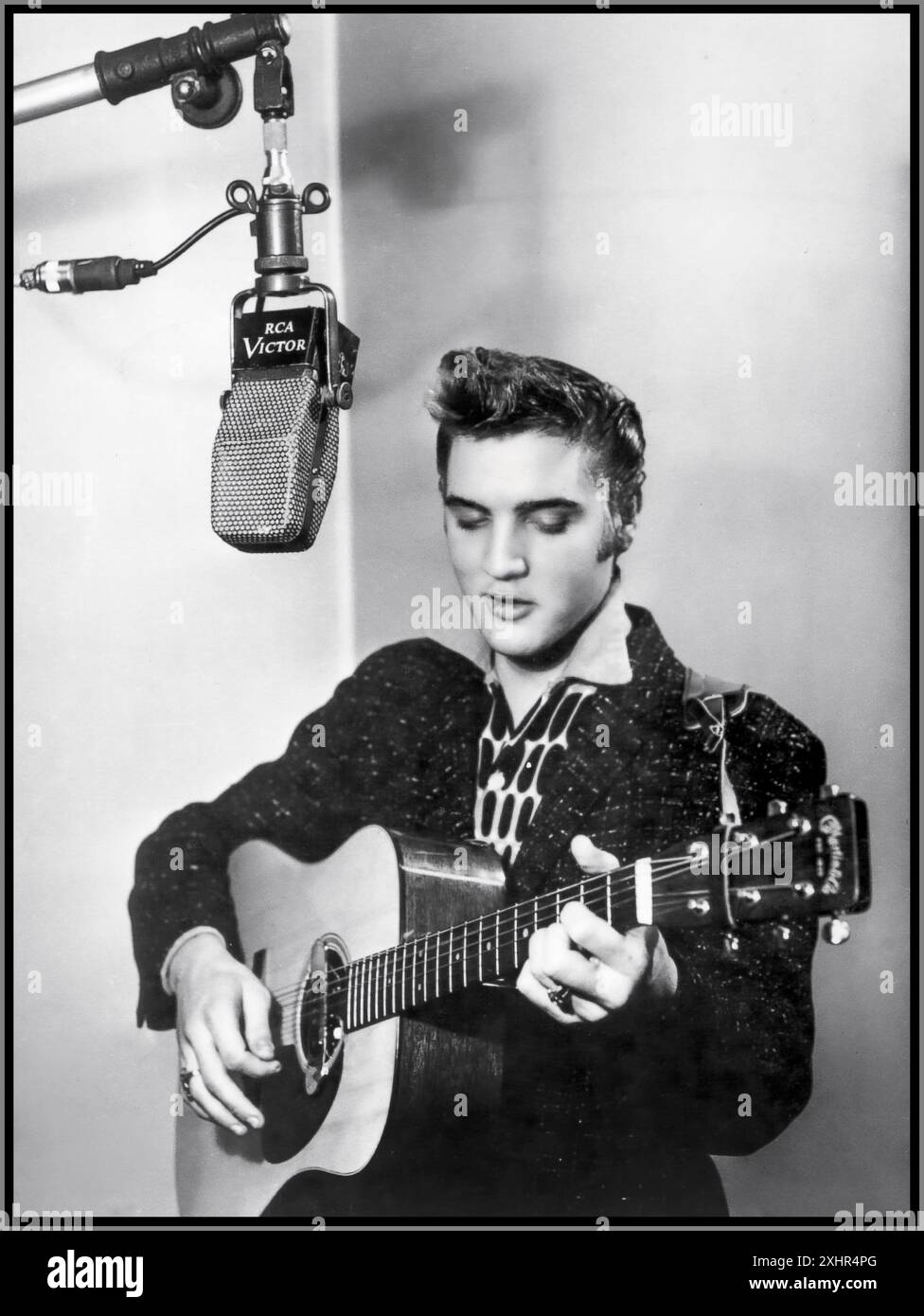 ELVIS PRESLEY ikonischer Popstar in den 1950er Jahren zu Beginn seiner Karriere, sang und spielte seine Gitarre in einem RCA Victor Aufnahmestudio mit Mikrofon der Ära. Hollywood USA 1955 Stockfoto ELVIS PRESLEY ikonischer Popstar in den 1950er Jahren zu Beginn seiner Karriere, sang und spielte seine Gitarre in einem RCA Victor Aufnahmestudio mit Mikrofon der Ära. Hollywood USA 1955 Stockfoto