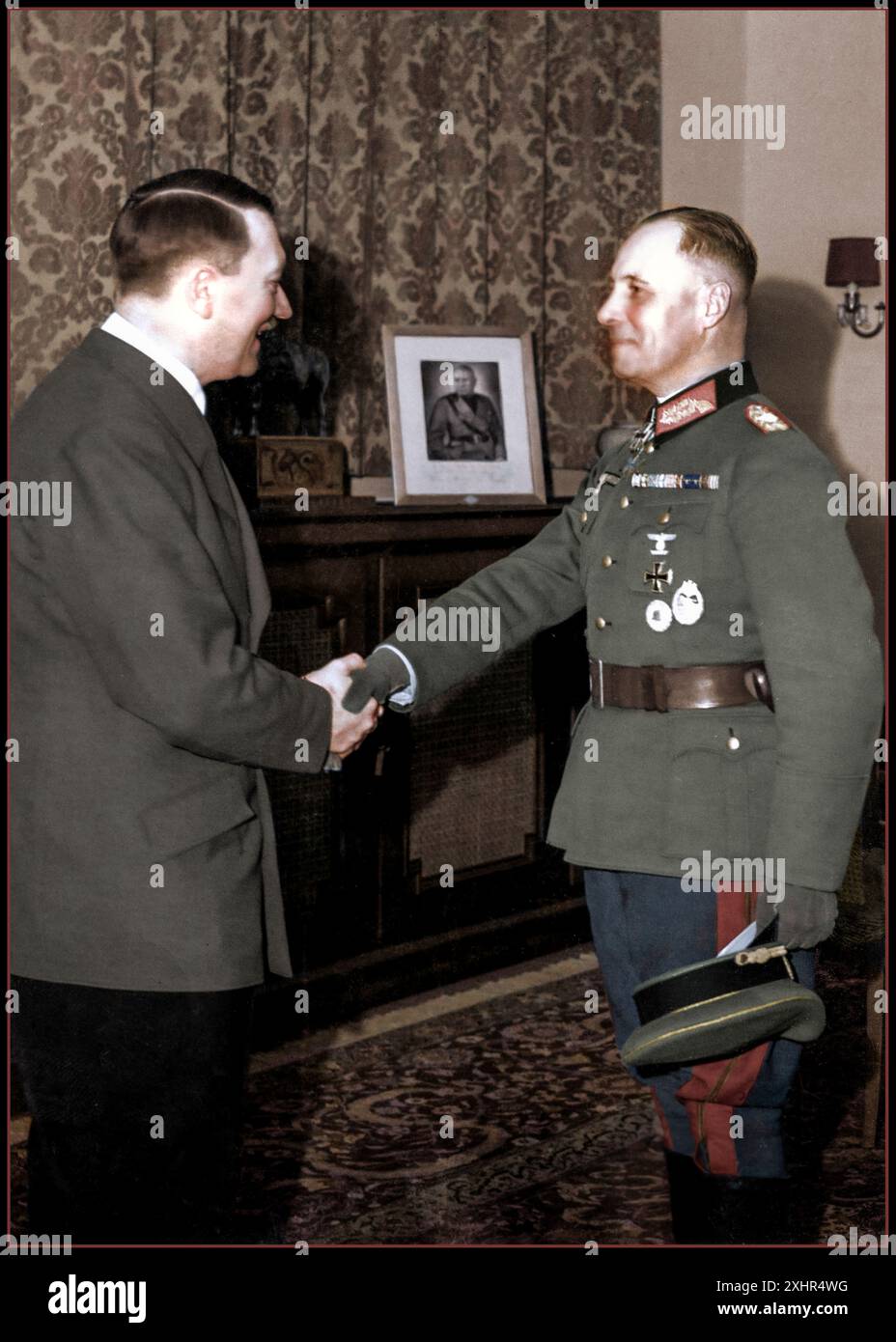 1941. Weltkrieg Adolf Hitler gratuliert General Erwin Rommel zu seiner Medaille mit Eichenlaub an das Ritterkreuz. Eine der höchsten militärischen Ehren des Nazi-Deutschlands. Porträt von Mussollini auf dem Sideboard dahinter. Berlin Nazi Deutschland Weltkrieg Stockfoto