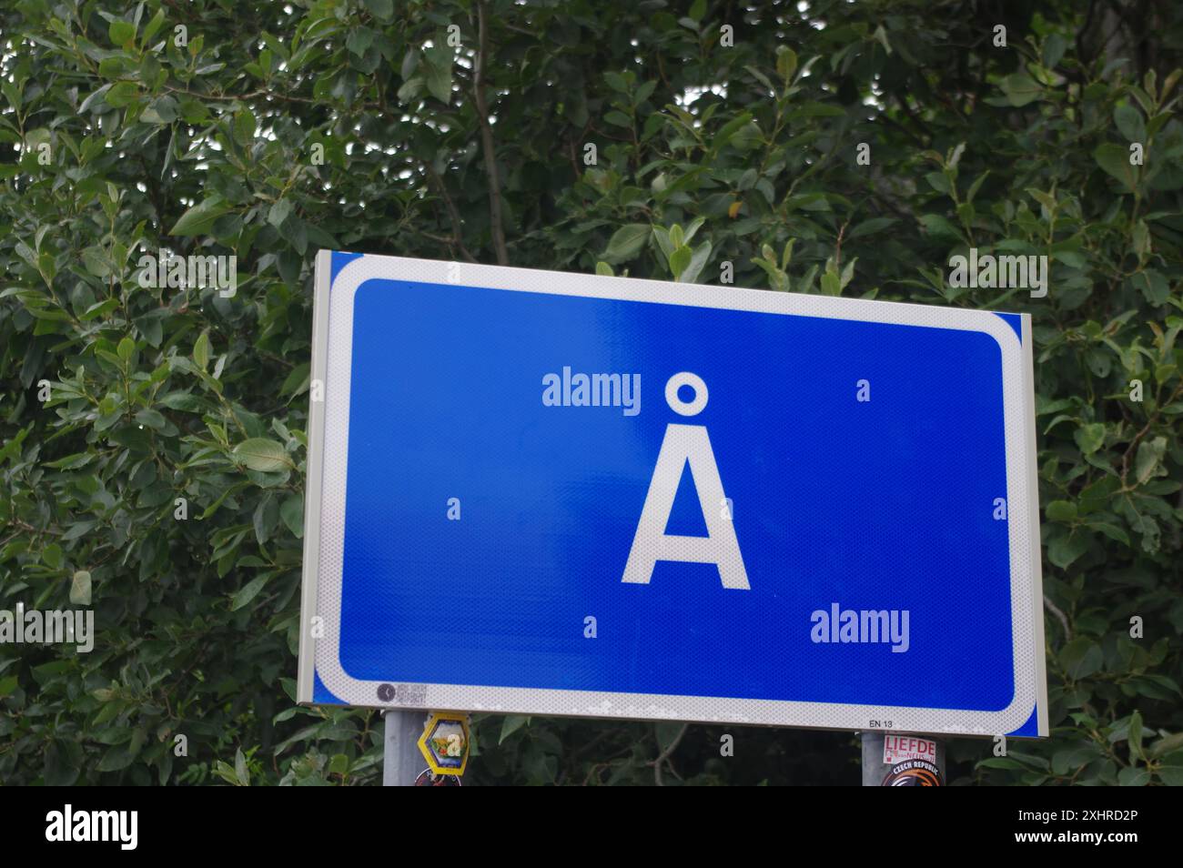 Blaues Straßenschild mit weißem Rahmen und dem Buchstaben A vor einem Hintergrund von dichtem grünem Laub, die südlichste Stadt in Lofoten, Moskenes, Nordland Stockfoto