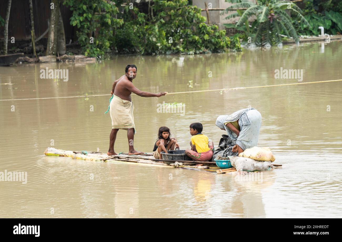 Morigaon, Indien. 4. Juli 2024. Die Menschen fahren mit einem Boot, um ein überflutetes Gebiet in einem von Überschwemmungen betroffenen Dorf im Bezirk Morigaon in Indien zu überqueren Stockfoto Morigaon, Indien. 4. Juli 2024. Die Menschen fahren mit einem Boot, um ein überflutetes Gebiet in einem von Überschwemmungen betroffenen Dorf im Bezirk Morigaon in Indien zu überqueren Stockfoto