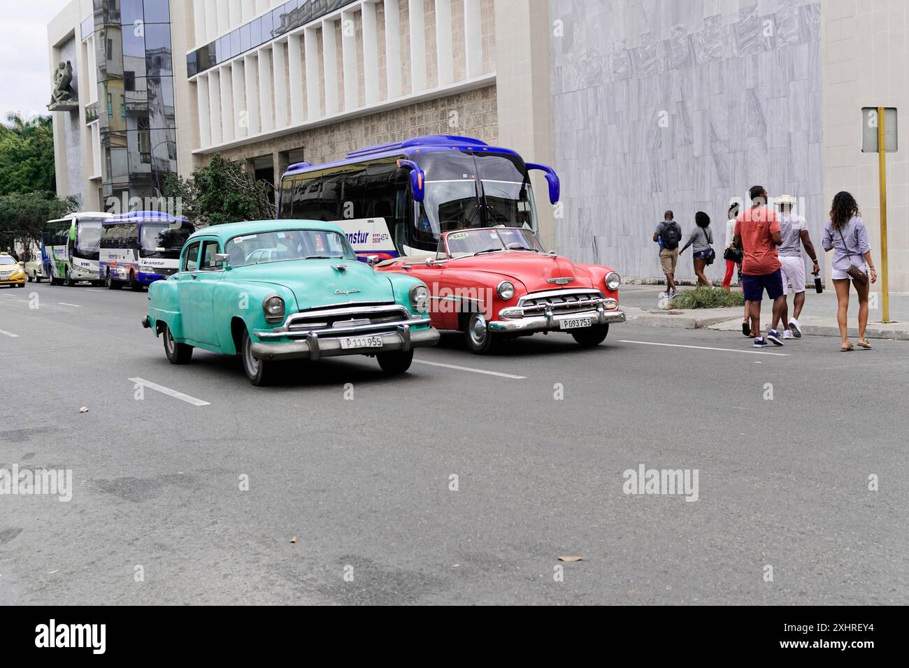 Havanna, Kuba, Zentralamerika, Retro-Autos in verschiedenen Farben fahren auf einer geschäftigen Stadtstraße, gesäumt von modernen Gebäuden und Menschen auf dem Gehweg Stockfoto