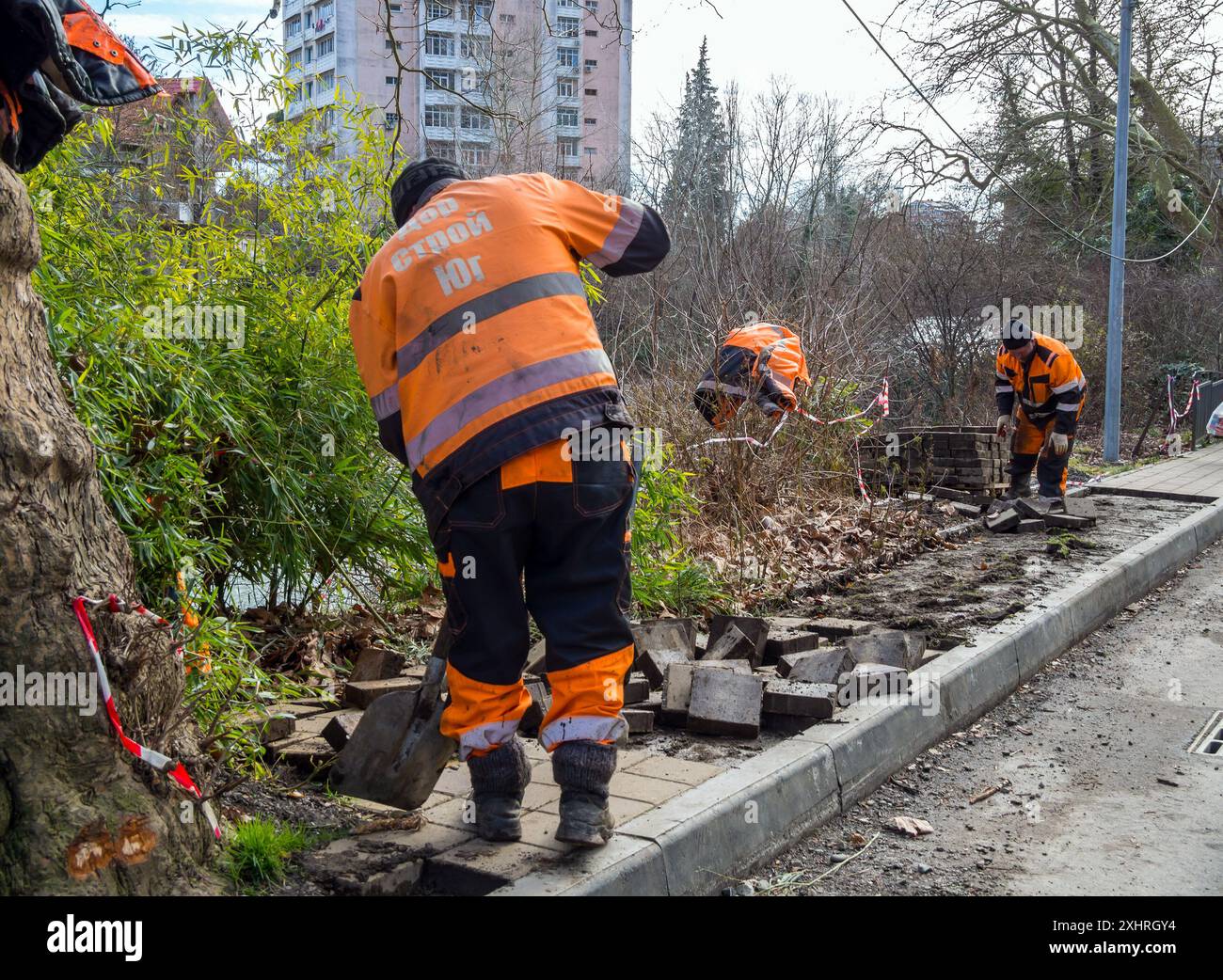 Sotschi, Russland - 16. Februar 2023: Arbeiter zerlegen alte Fliesen auf dem Bürgersteig, Samschitovaja Straße, Chosta, Sotschi Stockfoto