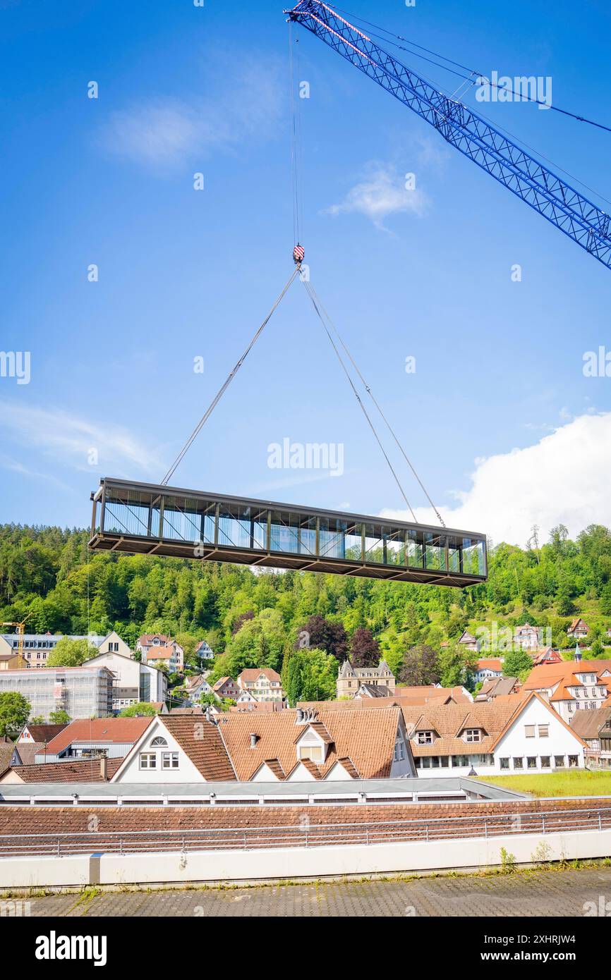 Ein Kran hebt eine Brücke in einem städtischen Gebiet mit grünen Hügeln im Hintergrund, Brücke hebt Hermann Hesse Eisenbahn, Calw, Deutschland Stockfoto