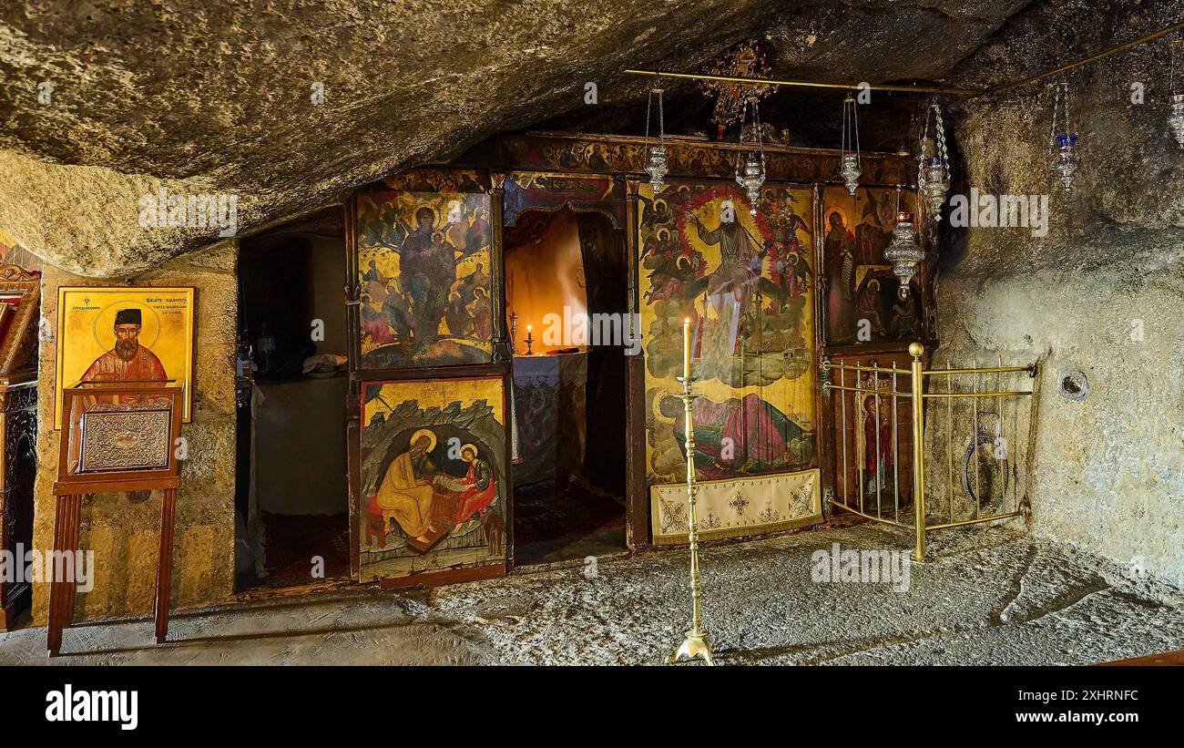 Orthodoxe Kirche in einer Steinhöhle mit Ikonostase, heiligen Bildern und Kerzen, die eine spirituelle Atmosphäre schaffen, Felsengrotte, Kloster tis Stockfoto