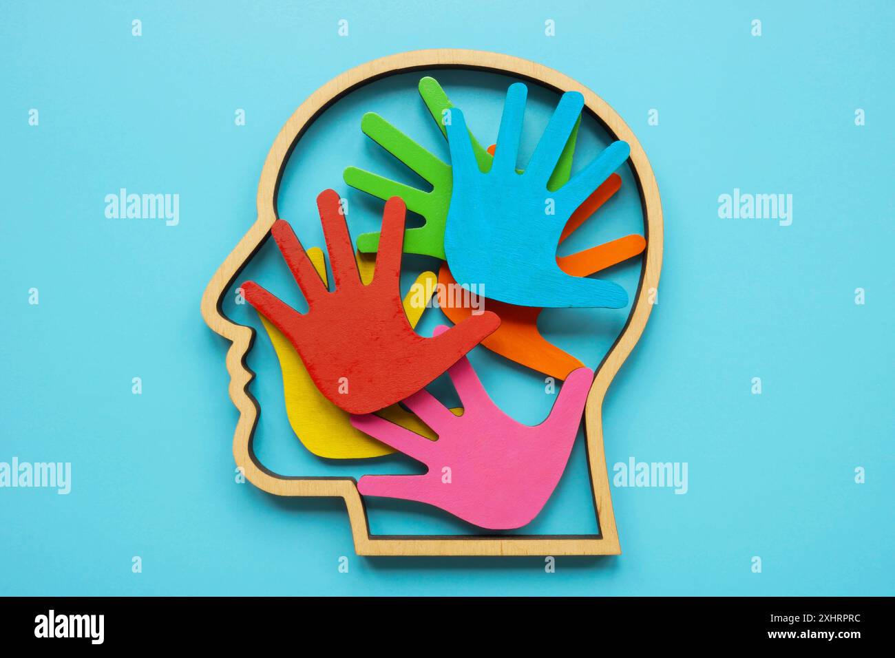 Kontur eines Kopfes und farbige Handflächen innen. Abstraktes Symbol von Autismus oder Neurodiversität. Stockfoto