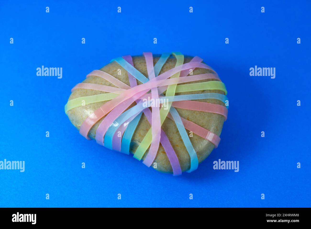 Stein mit mehreren bunten Gummibändern gebunden Stockfoto