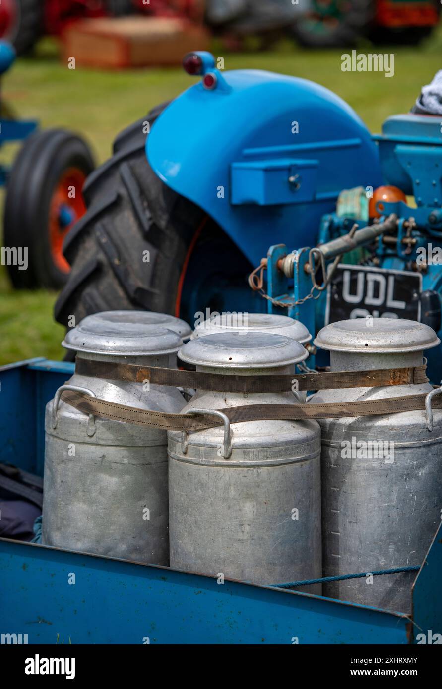 Eine Reihe von altmodischen Metallmilchkannen im Vintage-Stil auf der Rückseite eines Vintage-Traktors auf der isle of wight County Show in großbritannien Stockfoto