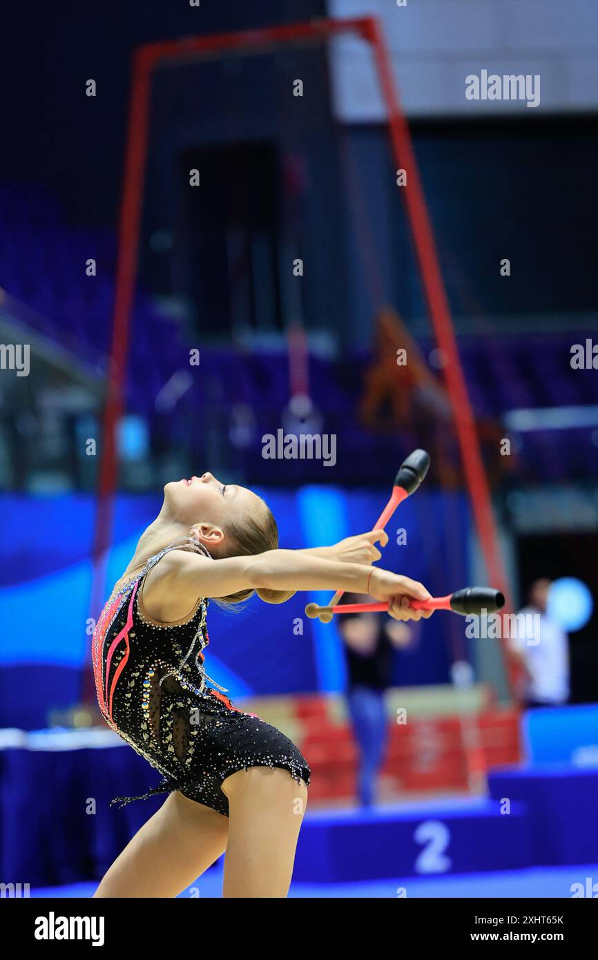 Eine junge Turnerin zeigt Akrobatik, Kunstfertigkeit und Leichtathletik in ihrer Routine bei einem Wettkampf Stockfoto
