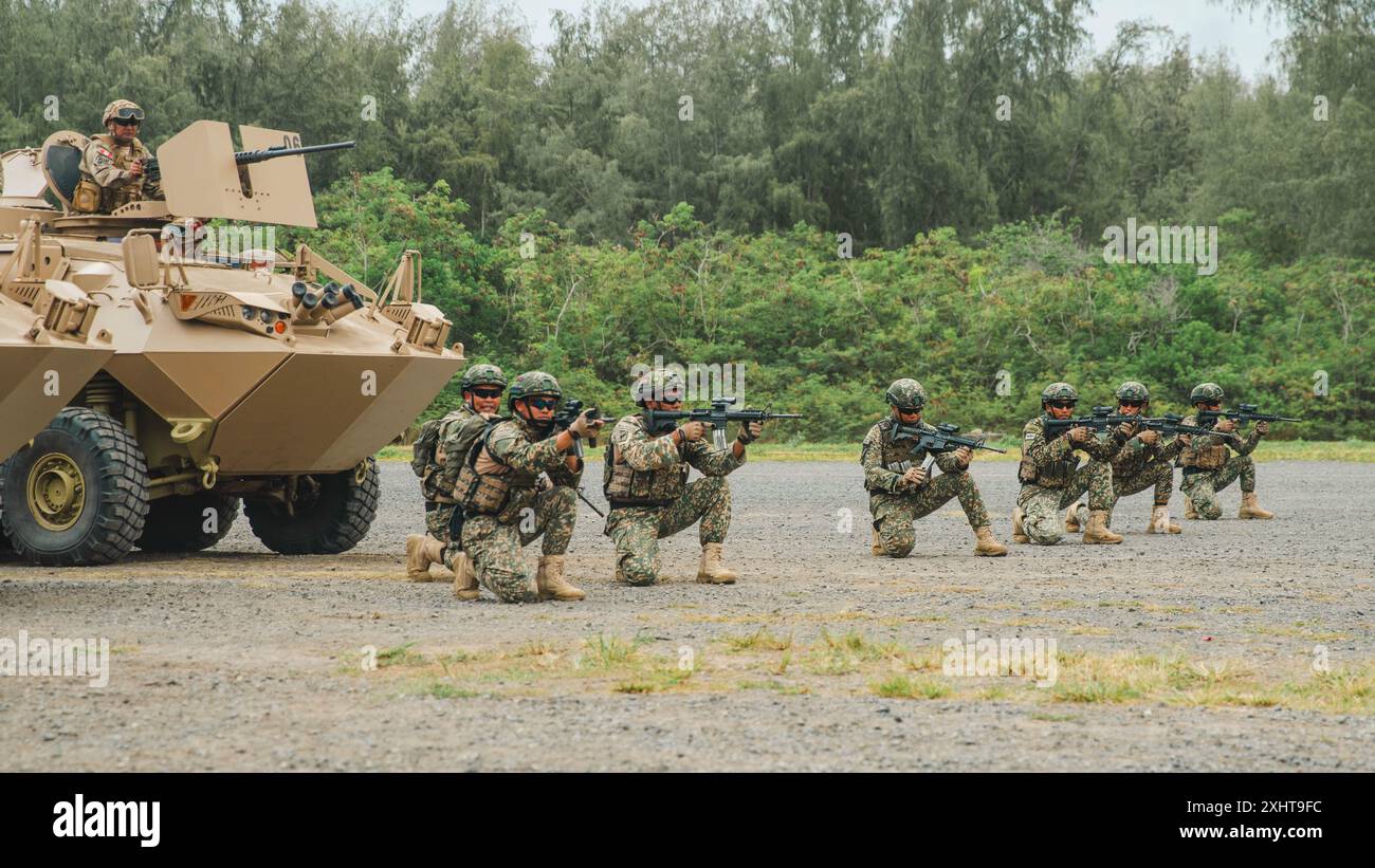 Peruanische Marineinfanterie-Marineinfanterie und malaysische Soldaten, die dem 8. Bataillon (Para), dem Royal Ranger Regiment, der 10. Fallschirmbrigade, zugewiesen wurden, halten eine Sicherheitsposition, nachdem sie in ein mechanisches Infanterie-Tauchtraining auf dem Marinekorps-Trainingsgebiet Bellows, Waimanalo, Hawaii, während der Übung Rim of the Pacific (RIMPAC) 2024, 13. Juli, eingesetzt wurden. 29 Nationen, 40 Überlandschiffe, drei U-Boote, 14 nationale Landstreitkräfte, mehr als 150 Flugzeuge und 25.000 Mitarbeiter nehmen vom 27. Juni bis 1. August auf den hawaiianischen Inseln Teil. Die weltweit größte internationale maritime Übung; RIMPAC Stockfoto
