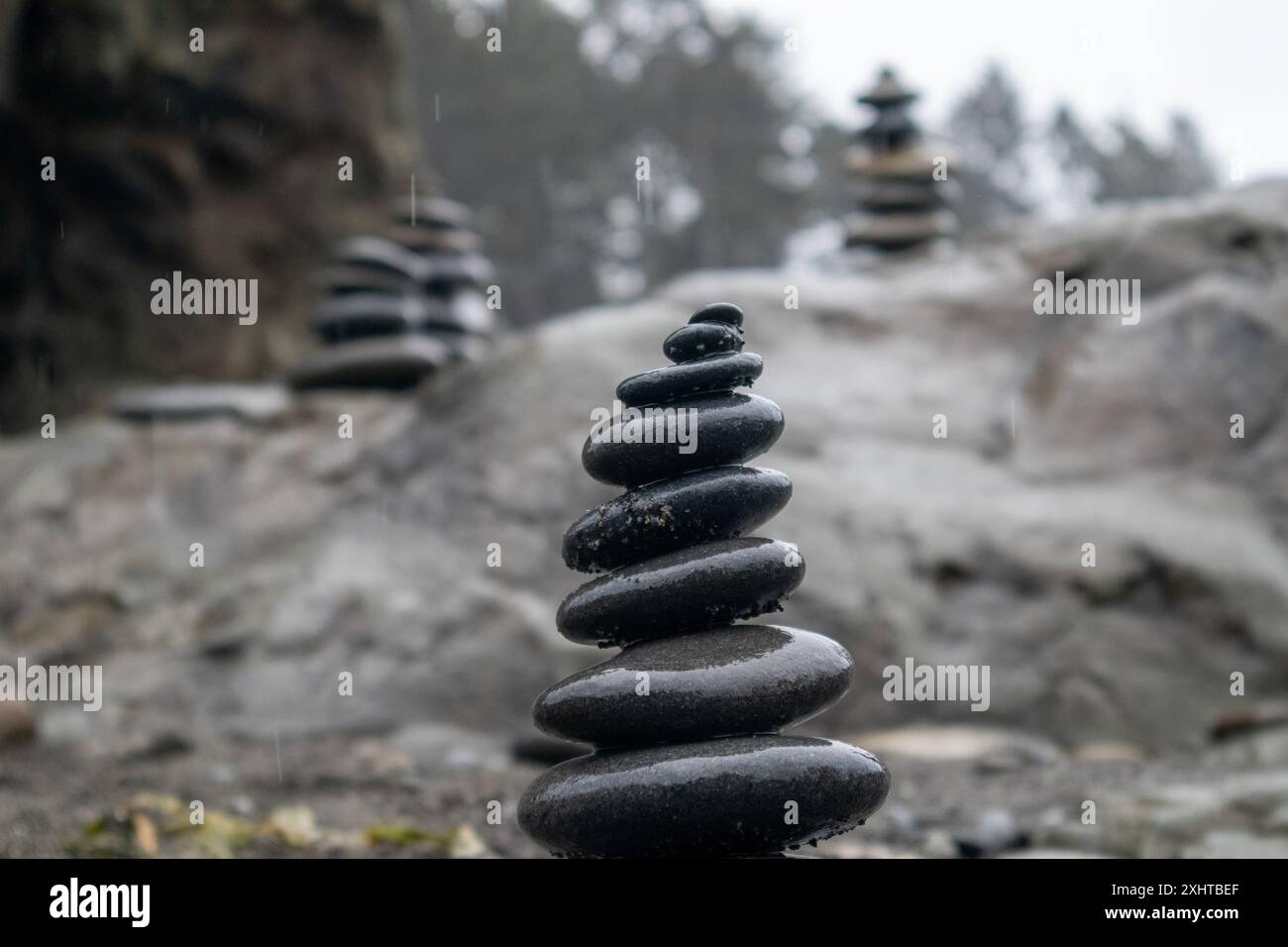 Vier Steinhügel sind zart auf einem großen Felsen platziert. Als Kompliment für den grauen Himmel vermitteln sie an einem regnerischen Tag im Ruby Beach Washington ein Gefühl der Ruhe. Hochwertige Fotos Stockfoto