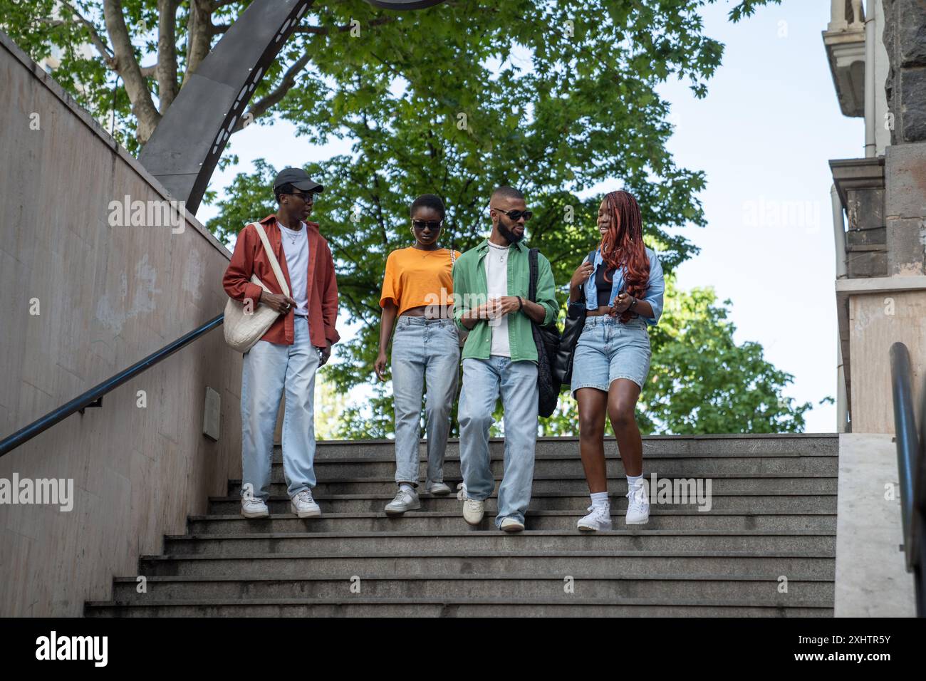 Eine Gruppe aufmerksamer afroamerikanischer Freunde diskutiert mit Begeisterung verschiedene Themen, spaziert im Freien Stockfoto