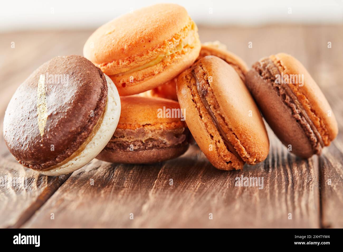 Mehrfarbige Macarons mit Kaffeearomen auf einem Holzhintergrund werden auf einer Folie gestapelt. Stockfoto