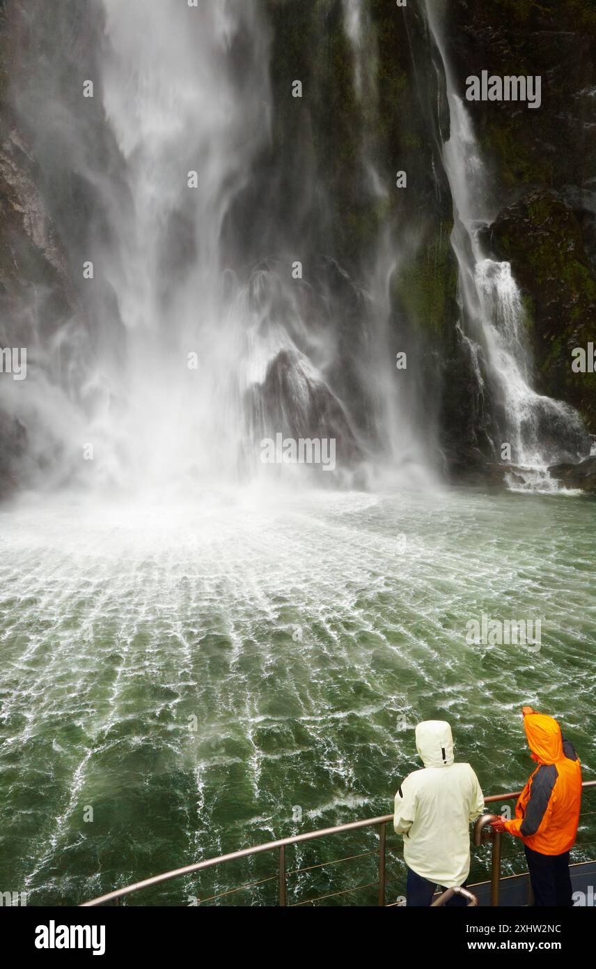 Menschen auf dem Boot in der Nähe von spektakulären Wasserfall, Milford Sound fiord, Neuseeland Stockfoto