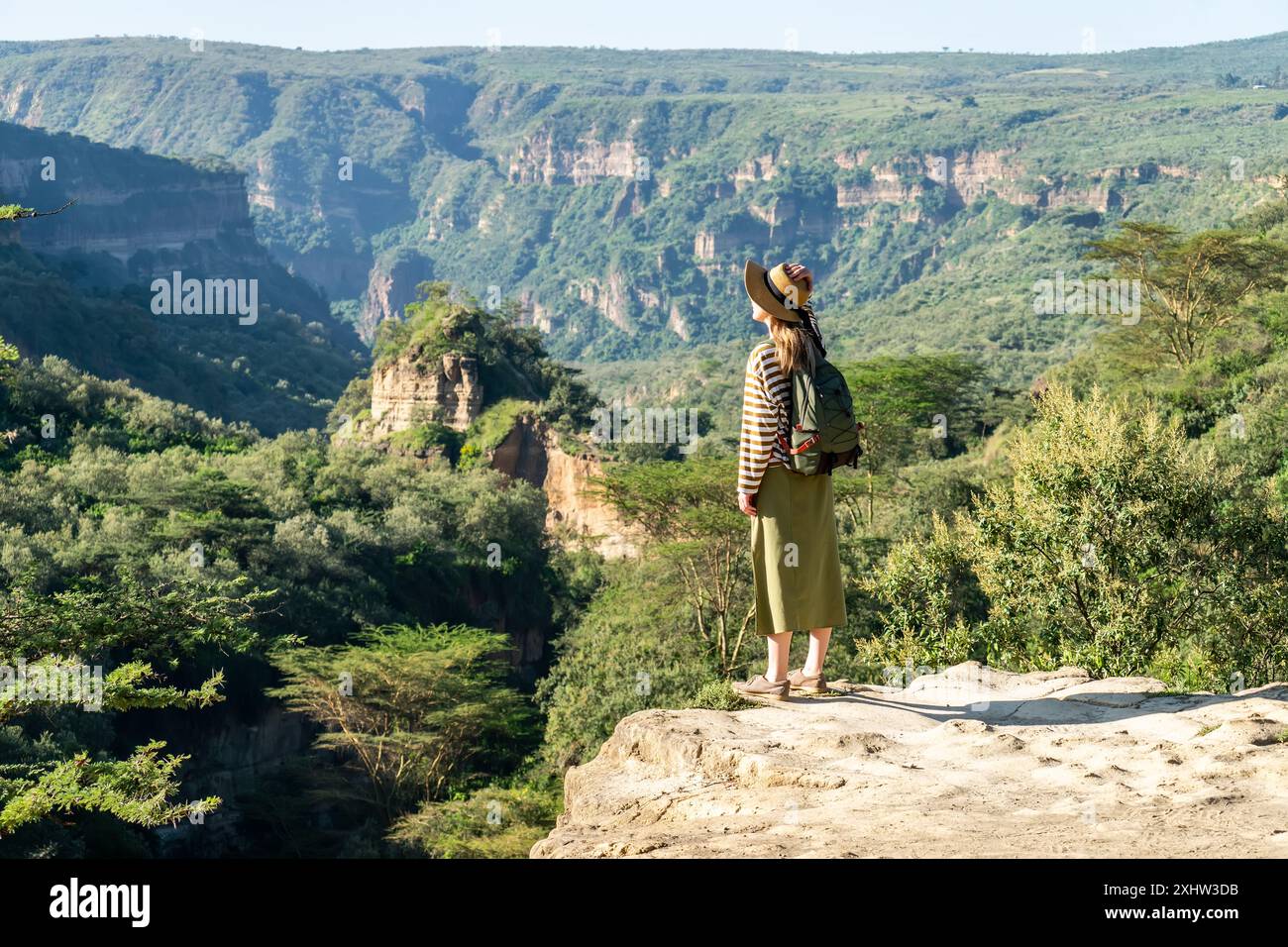 Mädchen, das am Rande des Berges steht und die Sonne genießt, sich in den Bergen entspannt, in der Natur wandert. Hell's Gate National Park, Kenia Stockfoto