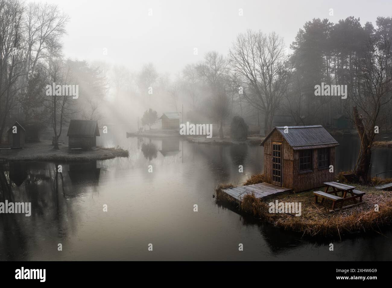 Szodliget, Ungarn - aus der Vogelperspektive eine traumhafte Winterszene am Szodliget Angelsee mit Fischerhütten und starkem Nebel an einem kalten Wintermorgen Stockfoto