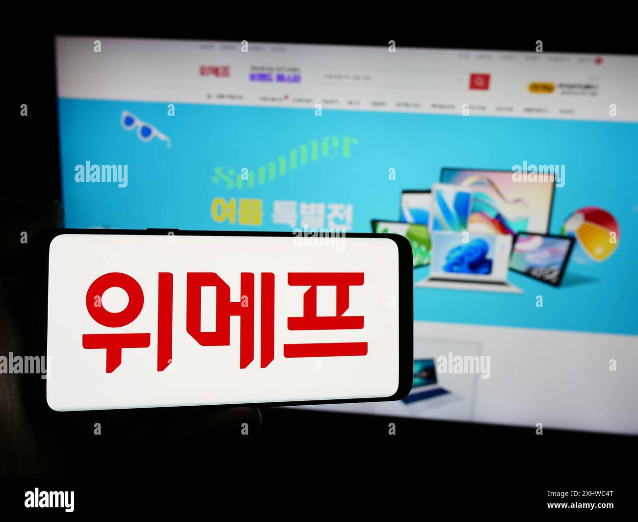Person mit Smartphone und Logo des südkoreanischen E-Commerce-Unternehmens Wemakeprice vor der Website. Schwerpunkt auf dem Display des Telefons. Stockfoto