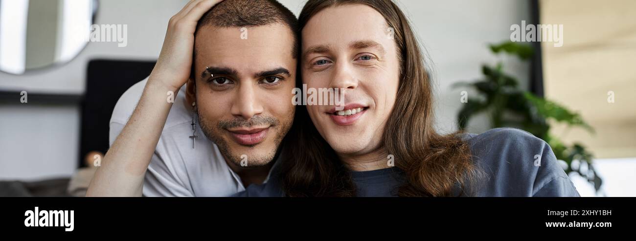 Ein junges schwules Paar teilt einen zärtlichen Moment in ihrem Schlafzimmer, ihre Liebe und Verbindung wird in ihrem liebevollen Blick deutlich. Stockfoto