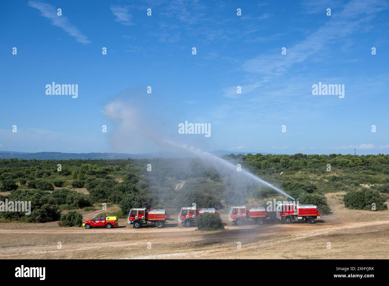 Coudoux, Frankreich. Juli 2024. Ein Feuerwehrwagen Bouches-du-Rhone betätigt seinen Feuerwehrschlauch, um den Konvoi während einer Schulung zu schützen. Alle an der Bekämpfung von Waldbränden beteiligten Akteure organisieren eine Ausbildung zum Schutz von Konvois und Feuerwehrleuten, die im Vorfeld eines heißen, trockenen Sommers, der den Waldbränden im Mittelmeerraum förderlich ist, eingreifen. Quelle: SOPA Images Limited/Alamy Live News Stockfoto