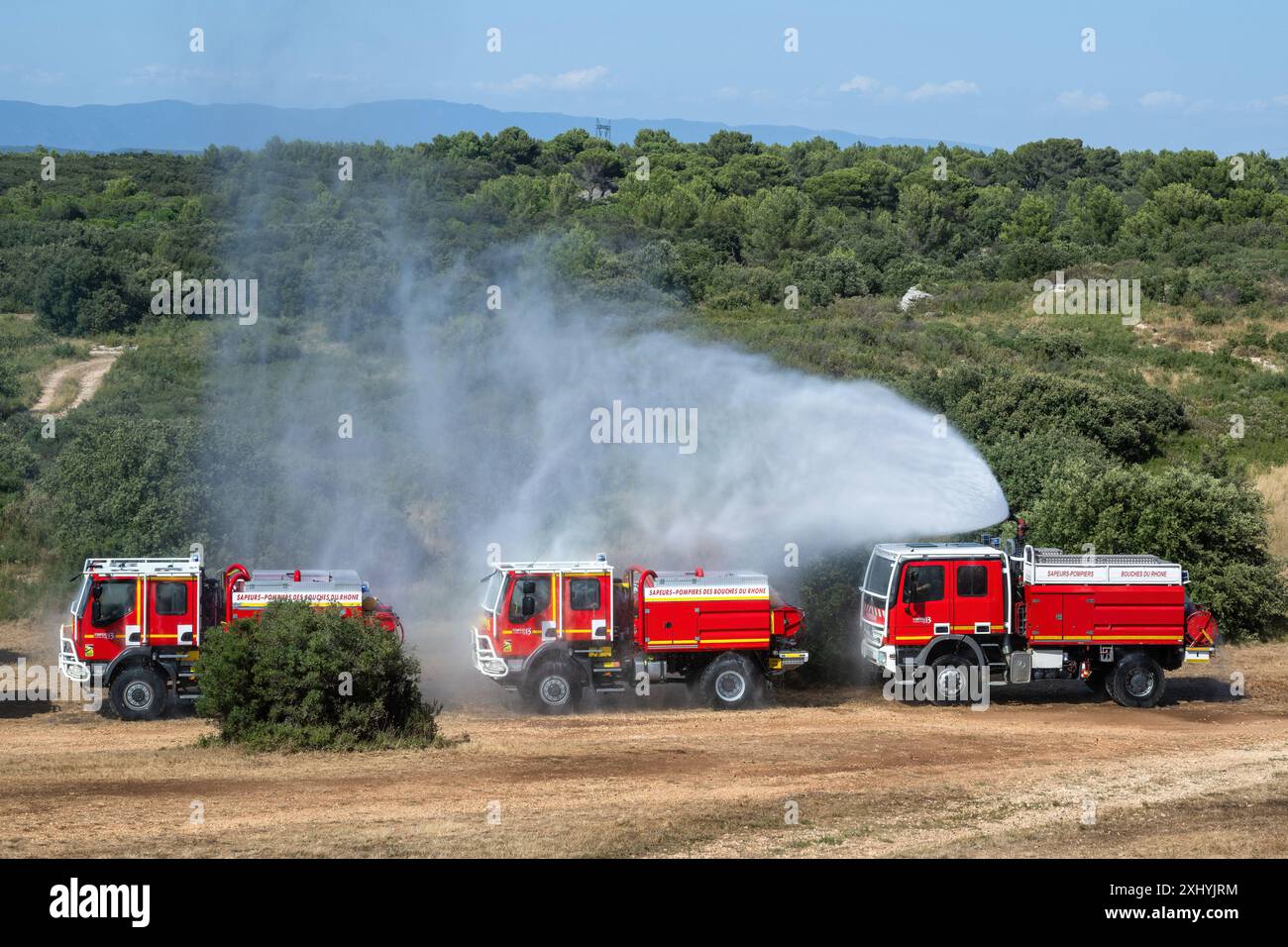 Coudoux, Frankreich. Juli 2024. Ein Feuerwehrwagen Bouches-du-Rhone betätigt seinen Feuerwehrschlauch, um den Konvoi während einer Schulung zu schützen. Alle an der Bekämpfung von Waldbränden beteiligten Akteure organisieren eine Ausbildung zum Schutz von Konvois und Feuerwehrleuten, die im Vorfeld eines heißen, trockenen Sommers, der den Waldbränden im Mittelmeerraum förderlich ist, eingreifen. Quelle: SOPA Images Limited/Alamy Live News Stockfoto