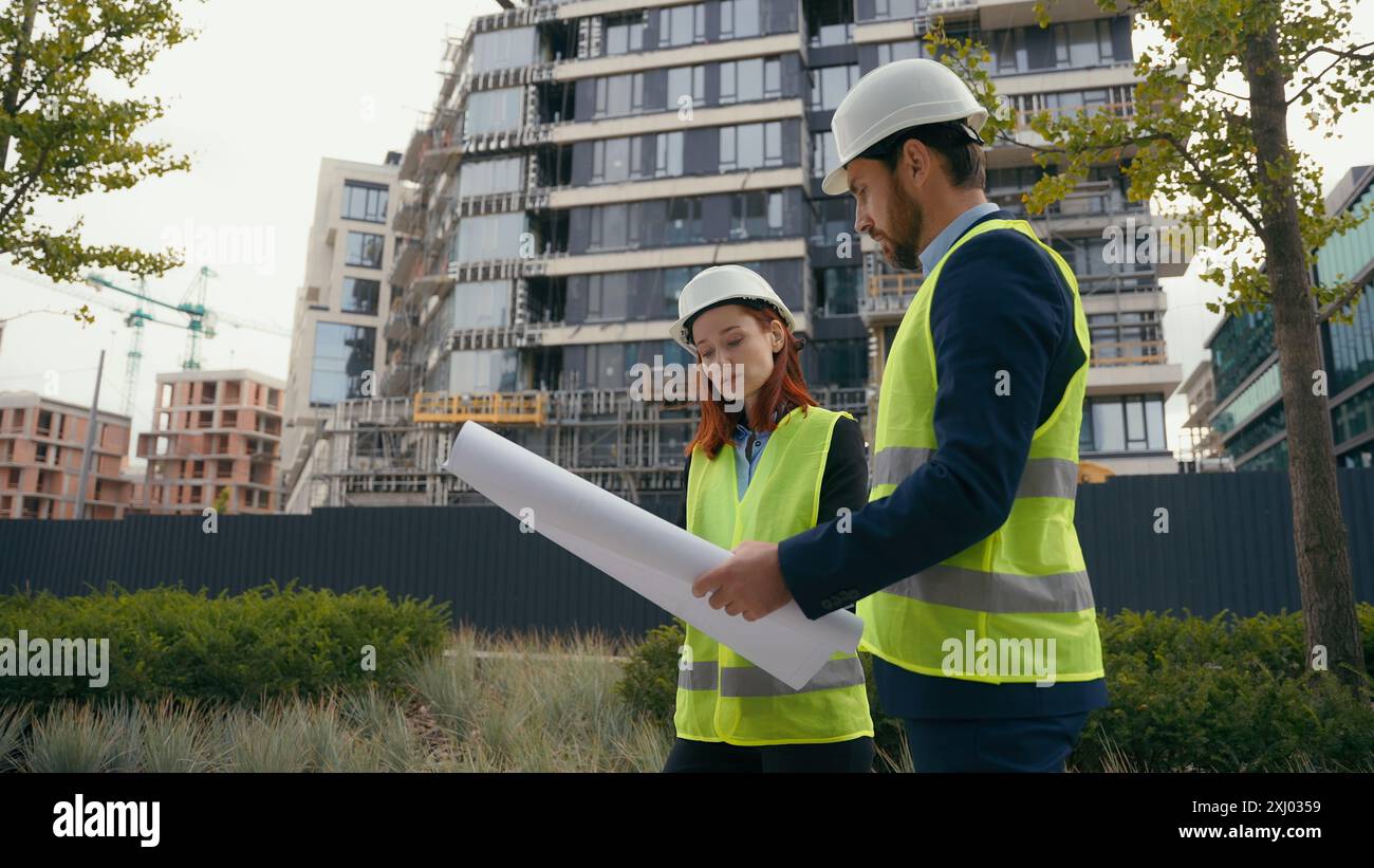Zwei Architekten Stadtbauarbeiter kaukasische Kollegen mit Sicherheitshut und reflektierender Weste sprechen über Stadtbauingenieure Stockfoto