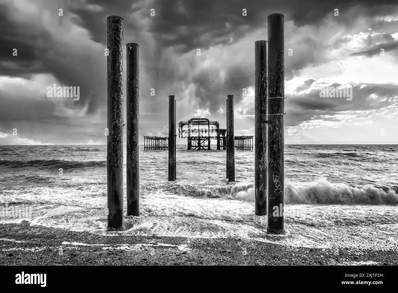 Ein Bild von Brightons West Pier vor einem Hintergrund dunkler, brütender Sturmwolken, alle in einem starken Schwarz-weiß-Ton Stockfoto