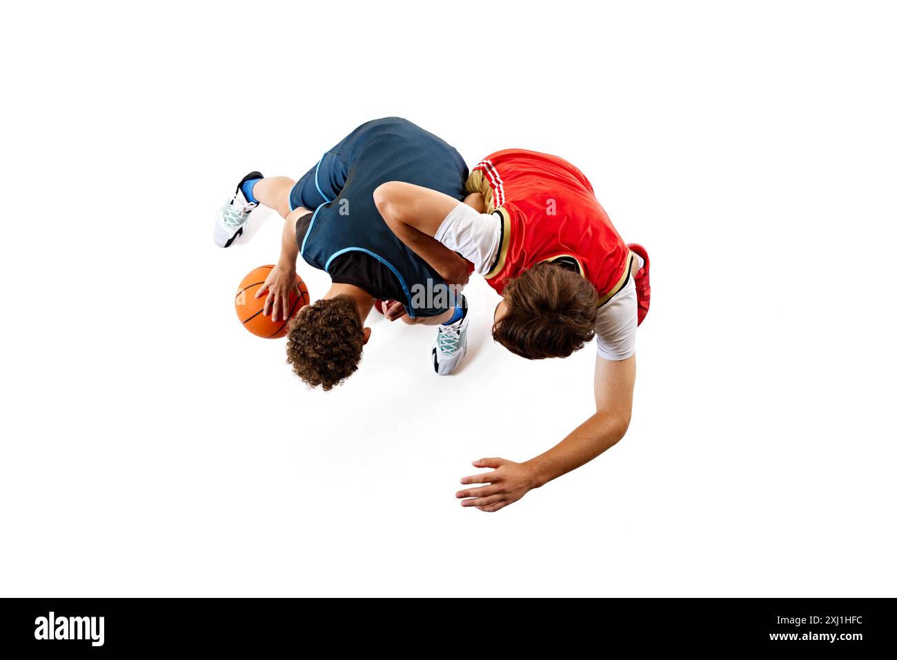Ein energiegeladener Moment im Basketballspiel, in dem zwei Spieler vor weißem Studiohintergrund um die Ballkontrolle wetteifern. Dribbeln. Luftaufnahme. Stockfoto