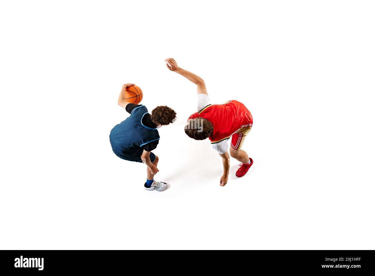 Dynamische Aufnahme von zwei jungen Basketballsportlern, die ihre Fähigkeiten vor weißem Studiohintergrund trainieren. Luftaufnahme. Stockfoto