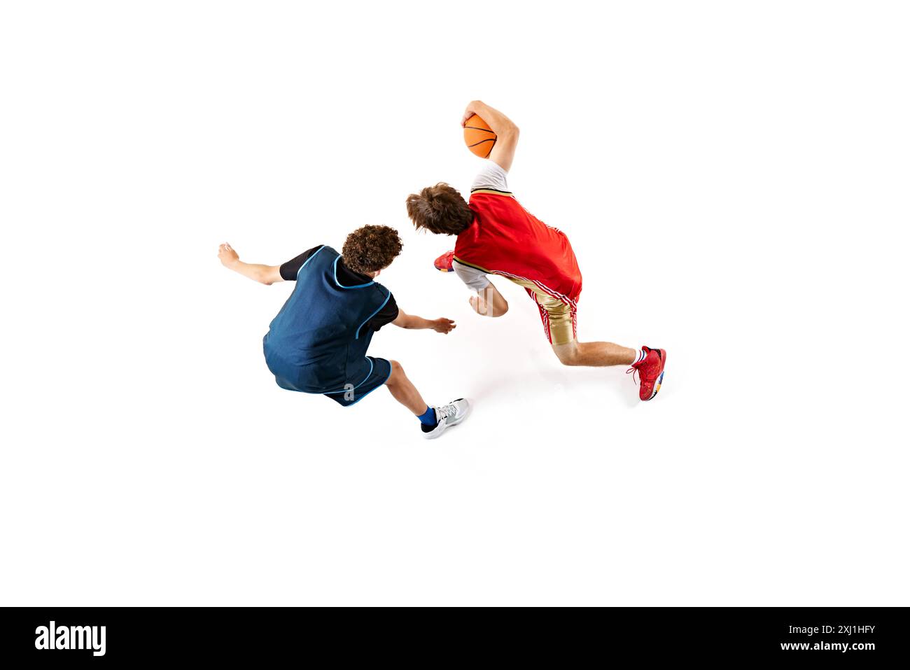 Dynamische Aufnahme von zwei jungen Basketballsportlern, die ihre Fähigkeiten vor weißem Studiohintergrund trainieren. Luftaufnahme. Stockfoto