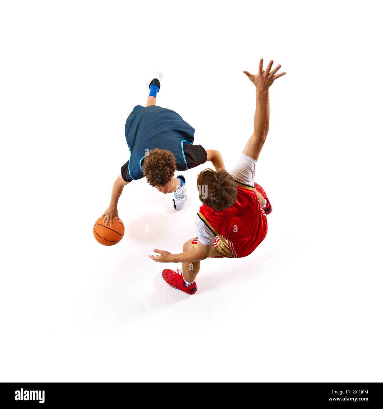 Der Basketballspieler in Blau versucht, den Verteidiger in Rot auszumanövrieren, was den Nervenkitzel des Spiels vor weißem Studiohintergrund verkörpert. Luftaufnahme. Stockfoto