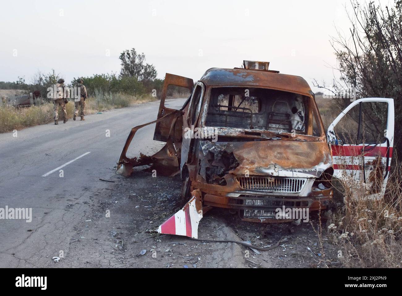 15. Juli 2024, Robotyne, Zaporischschschhia, Ukraine: Ukrainische Soldaten der 65. Separaten Mechanisierten Brigade gehen an dem zerstörten Ambulanzwagen an der Frontlinie bei Robotyne vorbei. Der unnachgiebige Druck der Ukraine, ihre Verbündeten dazu zu bewegen, Ziele innerhalb Russlands mit gespendeten Waffen zu treffen, könnte beginnen zu funktionieren, sagte Präsident Wolodymyr Zelenskij am 15. Juli 2024. Wenn diese Erlaubnis nicht erlaubt wird, wird die Ukraine ihre eigenen Waffen einsetzen, um Russland zu treffen. Viele seiner Verbündeten unter der Führung der USA setzen den Zielen Grenzen, die sie innerhalb Russlands treffen können. Etwas, was Kiew sagt, macht es imposant Stockfoto