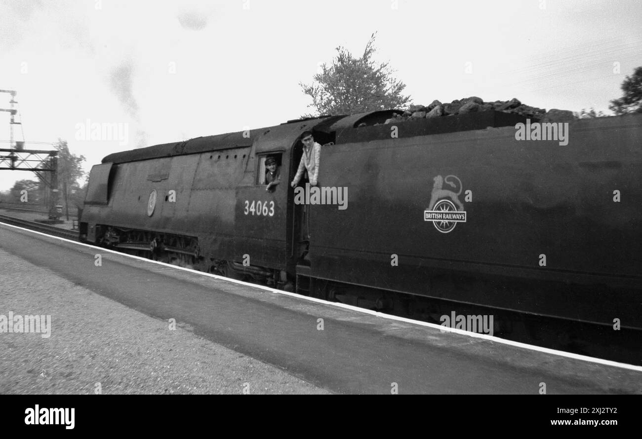 1950er Jahre, Historiker, Zugführer und Kohlerocker auf der Dampflok 34063, 229 Squadron parkte auf einem Bahnsteig. Die Lokomotive, bekannt als „Battle of Britain“, wurde 1947 bei den Brighton Locomotive Works gebaut und bis 1965 auf der West Country Line betrieben. Name und Logo der British Railways auf dem Kohlewagen, das von Abram Games entworfene Lion on on Wheel Emblem. Stockfoto