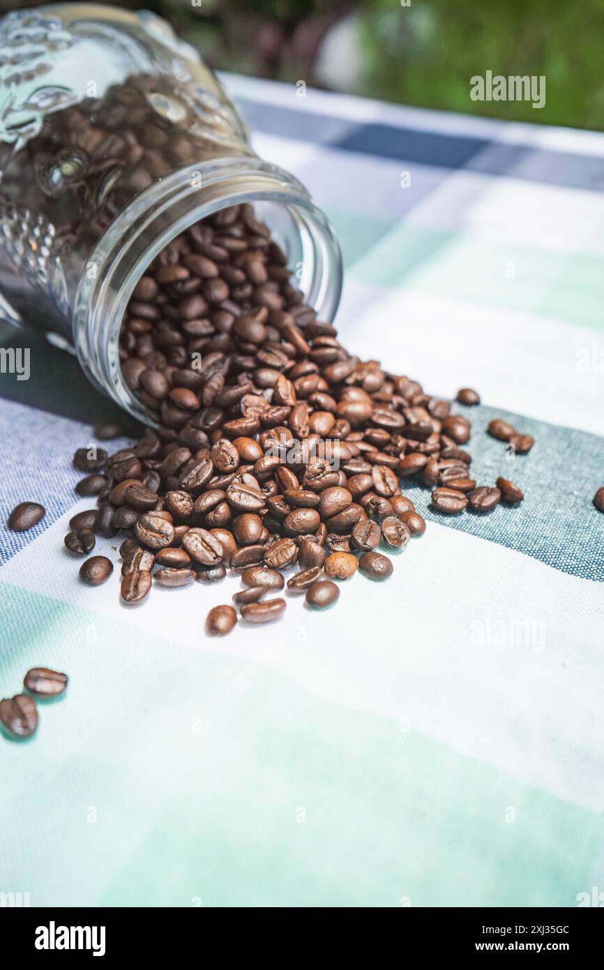 Auf einem Tisch geröstete Kaffeebohnen. Ein Glas Kaffeebohnen zum Mahlen. Arabica-Bohnen in einem Café Stockfoto