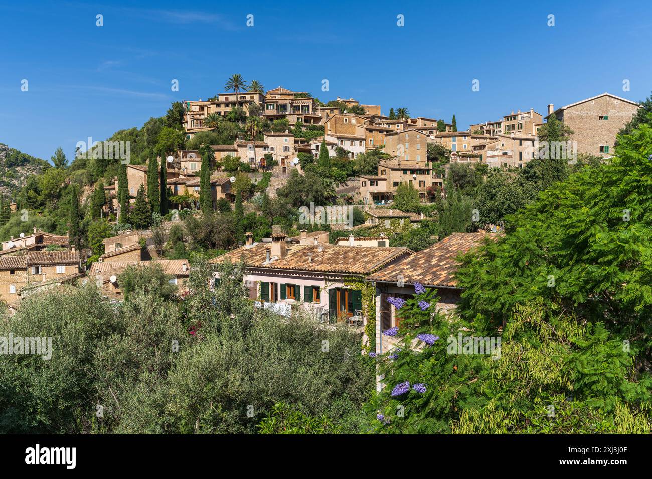 Atemberaubendes Stadtbild des kleinen Küstendorfes Deia auf Mallorca, Spanien. Traditionelle Häuser auf Hügeln, umgeben von grünen Bäumen. Tourist de Stockfoto