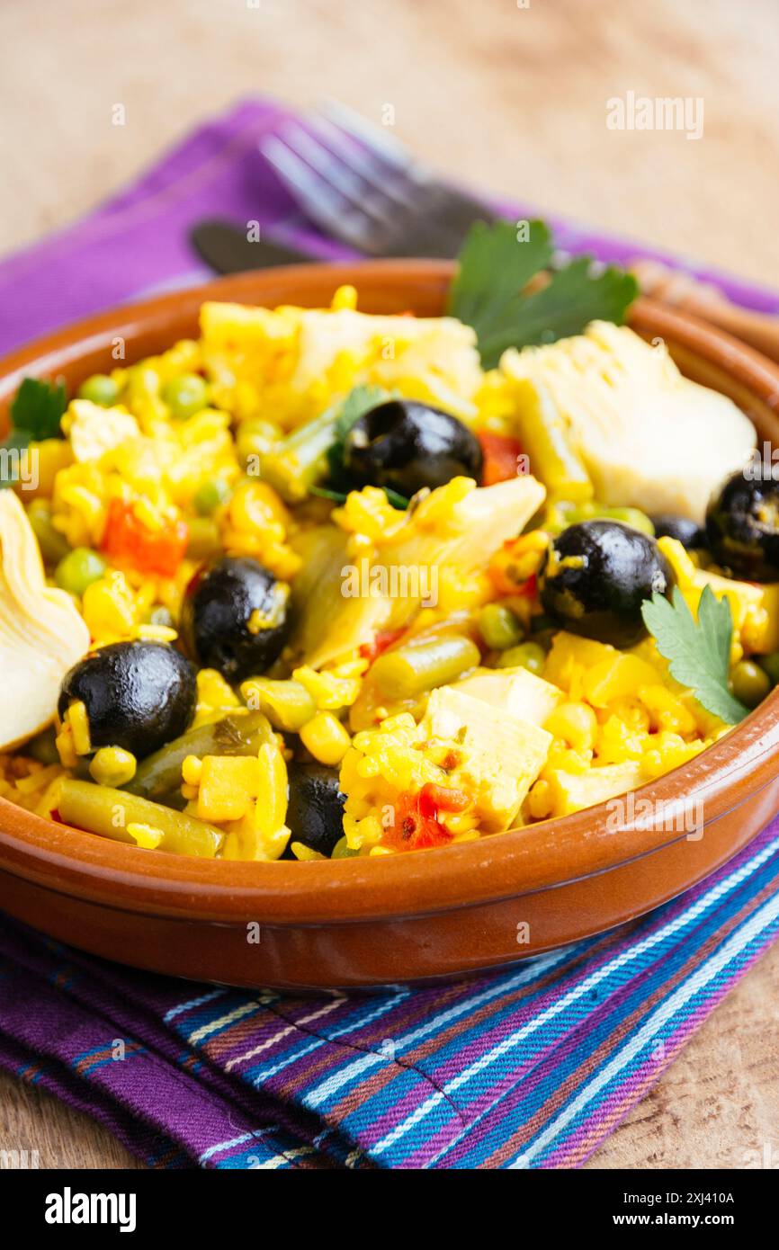 Vegetarische Paella mit Artischocke, schwarzen Oliven, grünen Bohnen und rotem Paprika. Stockfoto