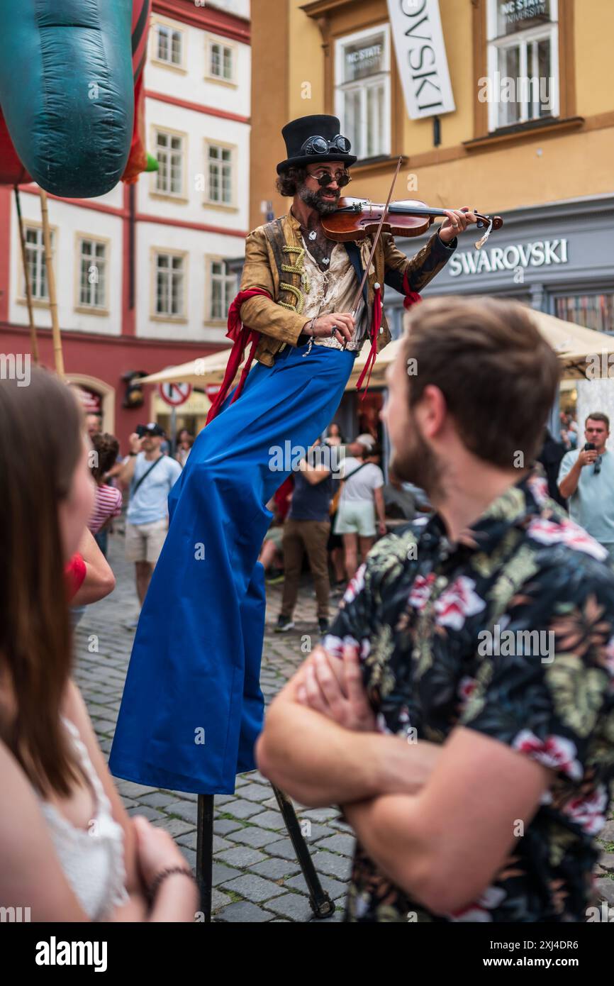 Der Künstler spielt Geige, während er während des Prager Straßentheaters Festival B auf Stelzen auf der Marionettenparade vom Marián-Platz zum Altstädter Ring spaziert Stockfoto