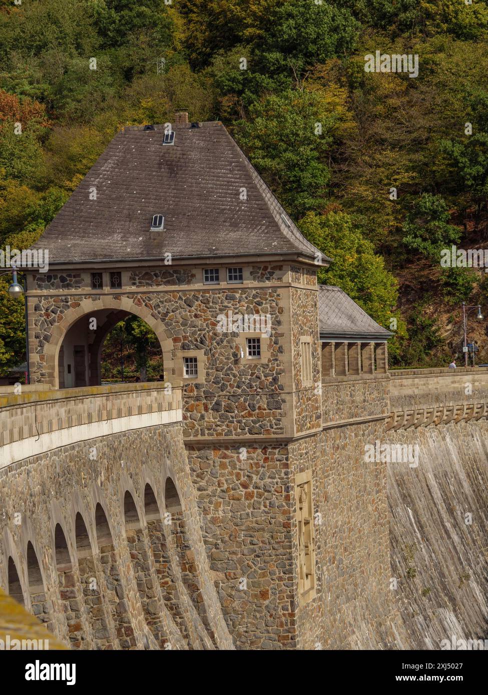 Nahaufnahme einer historischen Staumauer mit Torbogen vor einem herbstlichen Wald, waldeck, hessen, deutschland Stockfoto