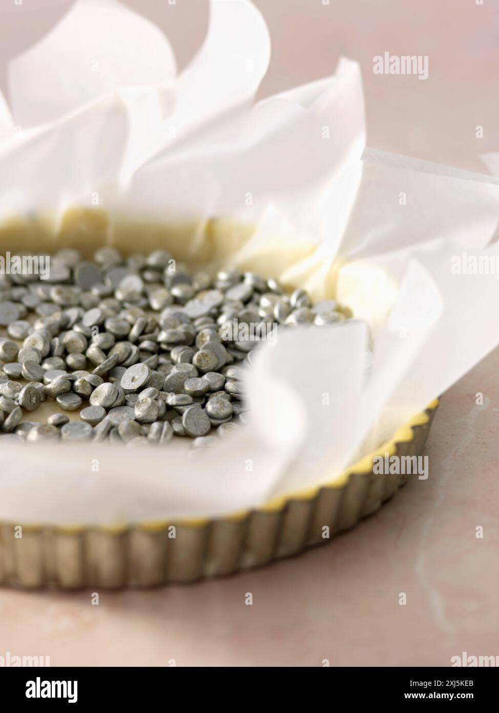 Decken Sie den Teig mit Backperlen ab, um ihn blind zu backen (Filmrezept: Erdbeertarte) Stockfoto