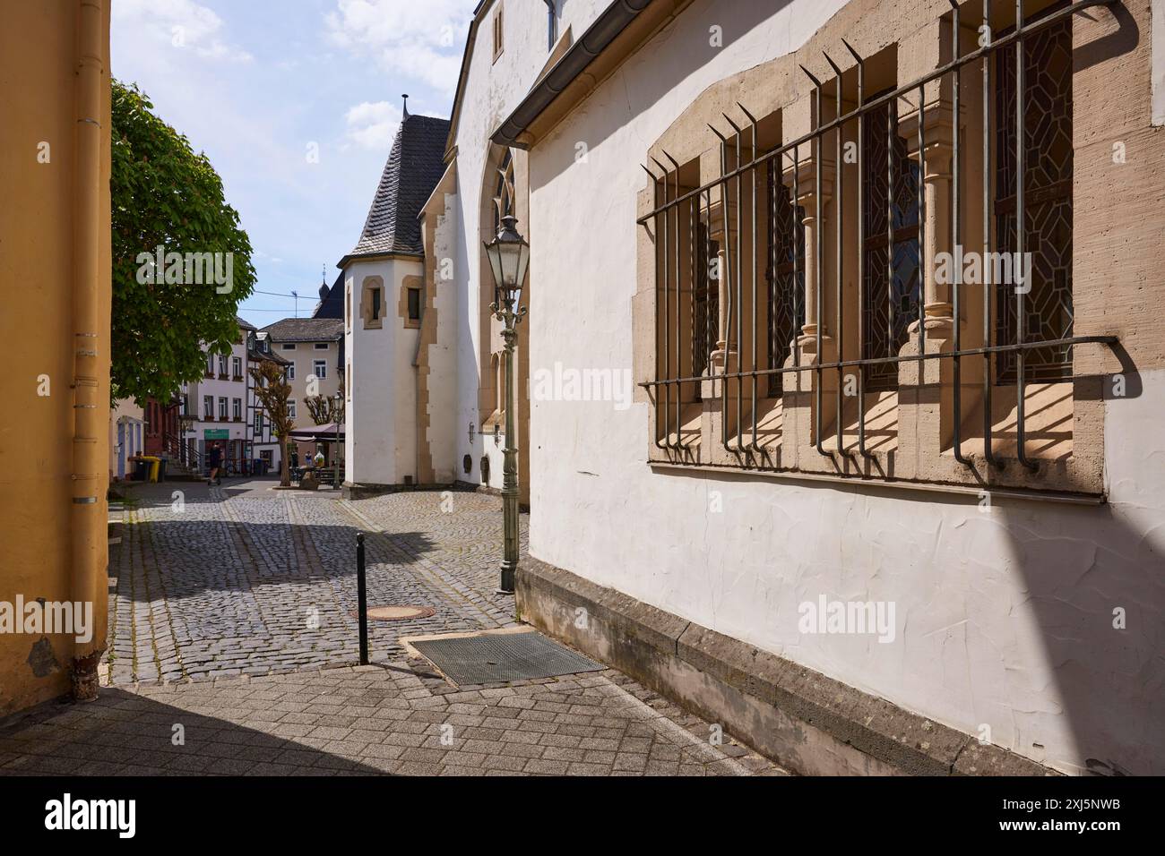 Fenster mit geschmiedetem Gitter zum Einbruchschutz der Kirche St. Johannes des Täufers mit Hintergrundbeleuchtung in Adenau, Eifel, Bezirk Ahrweiler Stockfoto