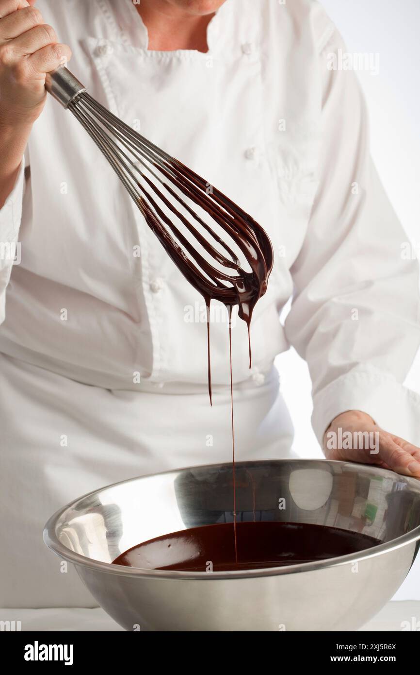 Mischen Sie das geschmolzene Schokoladen mit einem Schneebesen Stockfoto