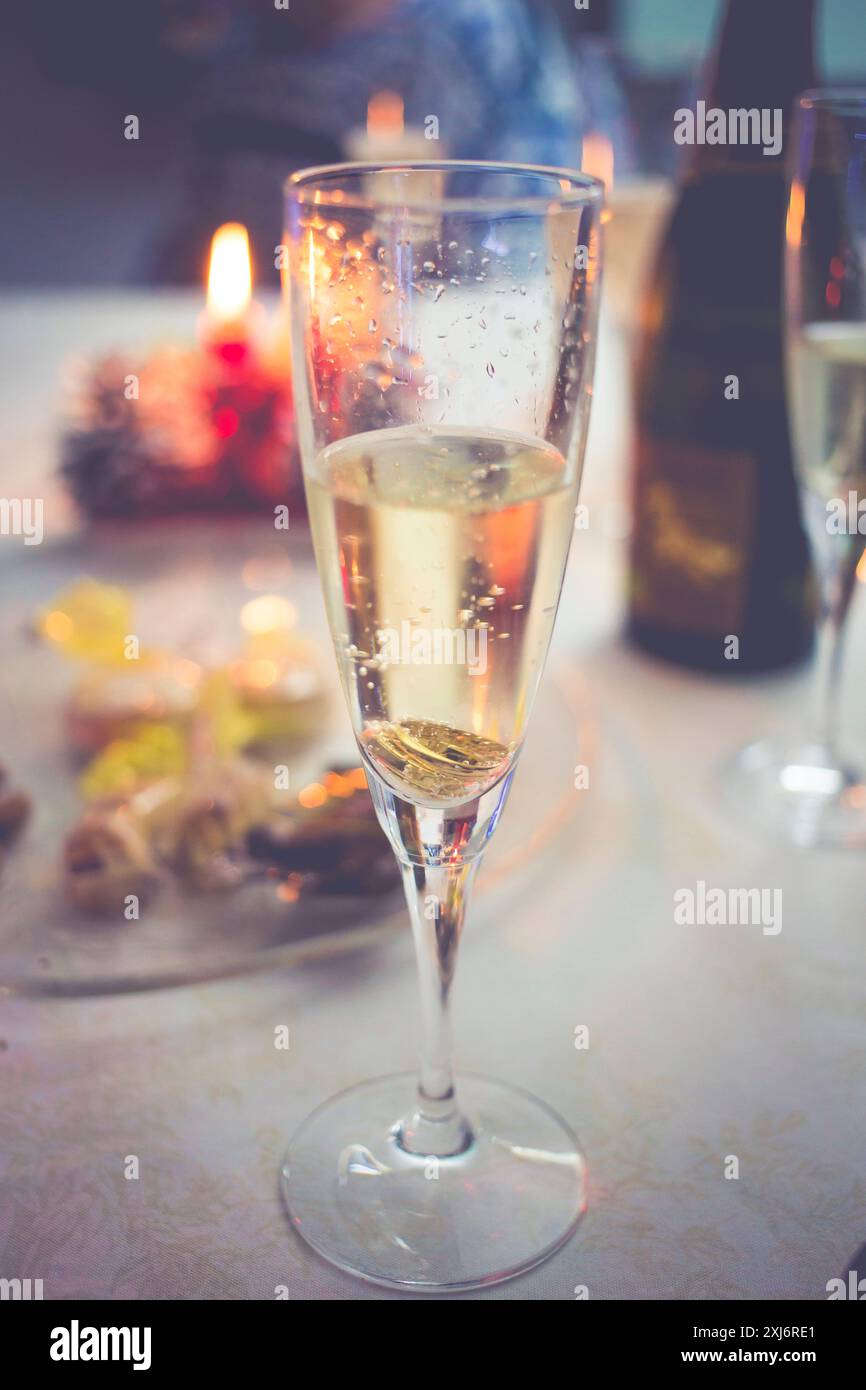Nahaufnahme eines Glases Champagner auf einem Tisch mit Häppchen und einer Kerze Stockfoto