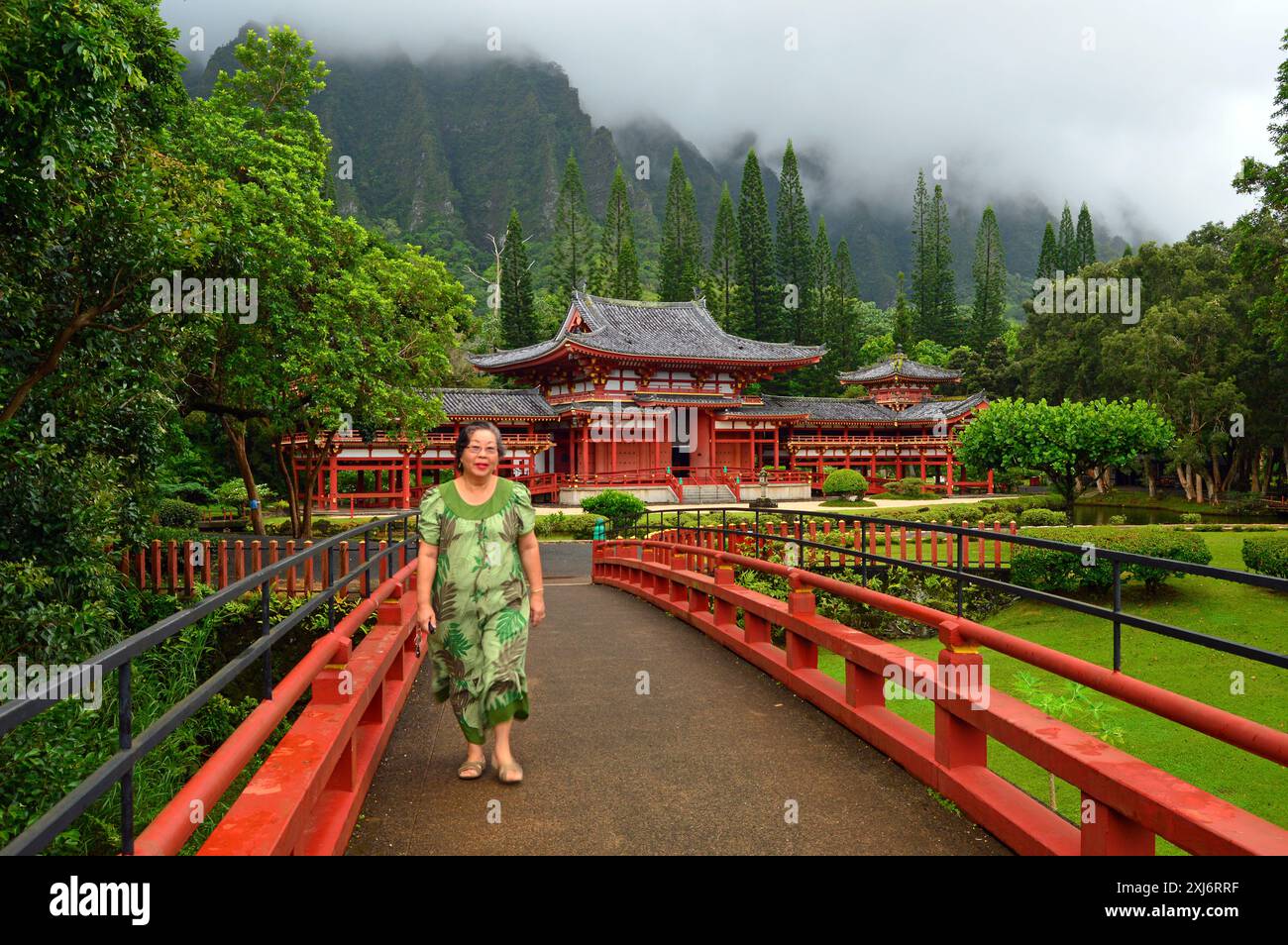 Eine ältere Frau läuft auf der Fußgängerbrücke am Byodo in Temple in Hawaii Stockfoto