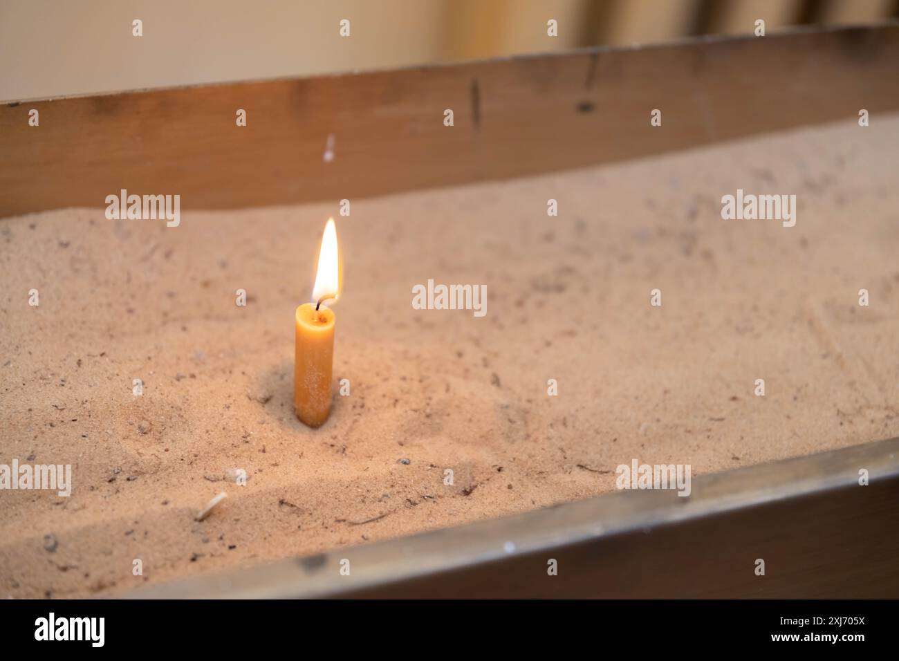 Kleine Kerze mit hellgelben Flecken auf hellem Hintergrund. Stockfoto